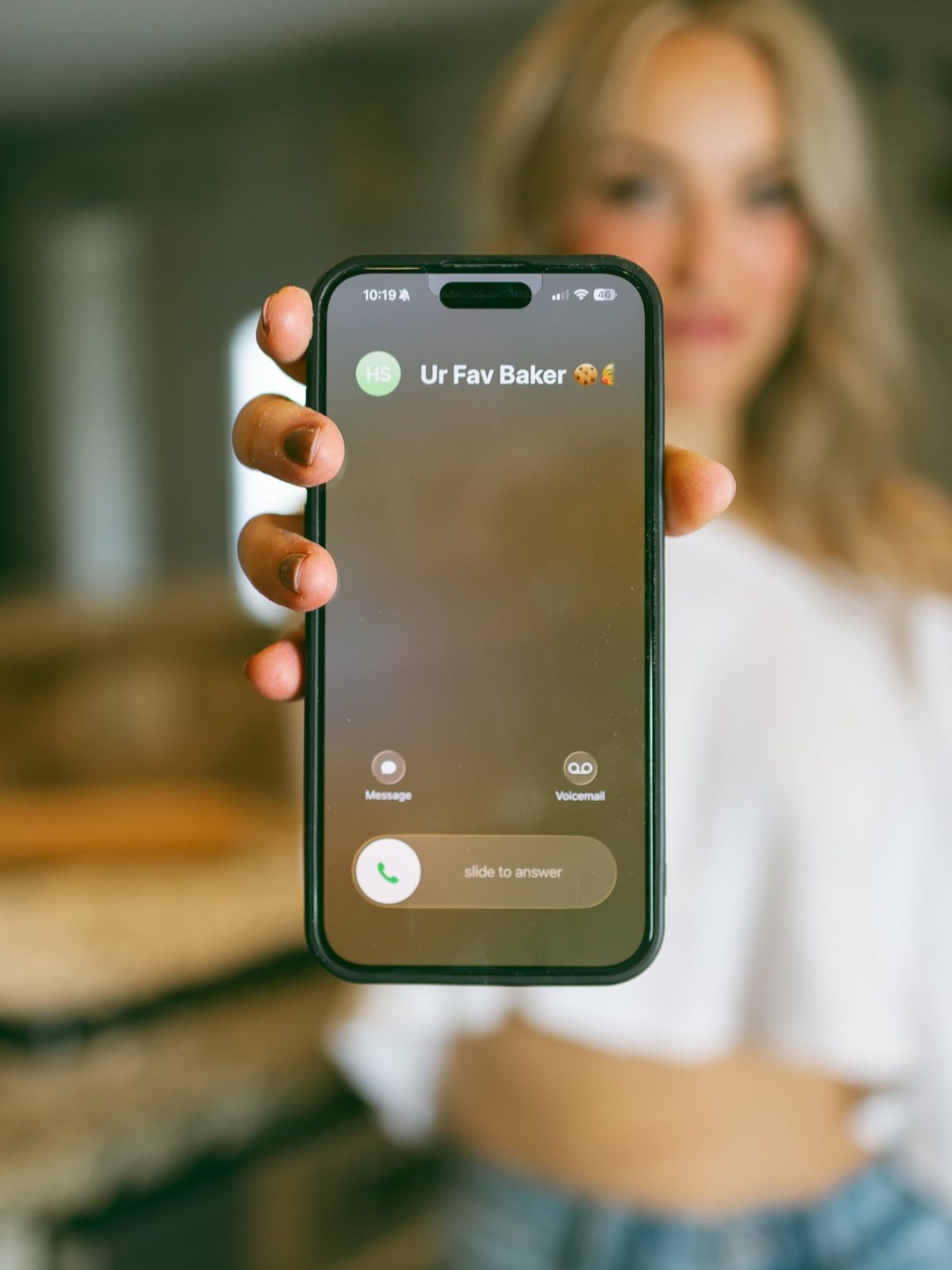 Ashley holding a phone showing an incoming call from Ur Fav Baker